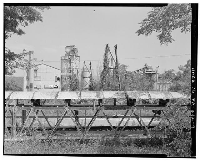 9. View east from western edge of complex. Collapsed overhead conveyor in foreground carried ganister down to the brickyard from crushing and grinding