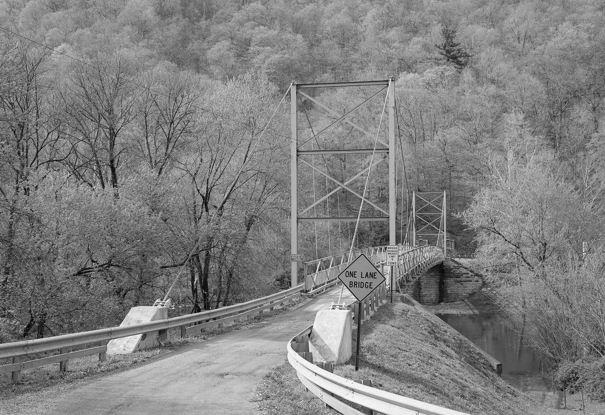 Eastern end of the Corbin Bridge, which carries Township Road 428 over the Raystown Branch Juniata River southwest of Huntingdon in Juniata Township, Huntingdon County, Pennsylvania, United States. Built in 1937, this suspension bridge is listed on the National Register of Historic Places.